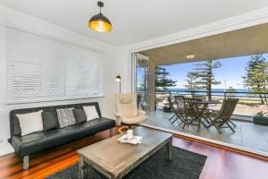een woonkamer met een zwarte bank en een tafel bij Beachfront on Golden Mile in Sydney