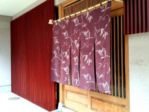 a curtain in a room with a red wall at Tsudoh Stay Hikoso in Kanazawa