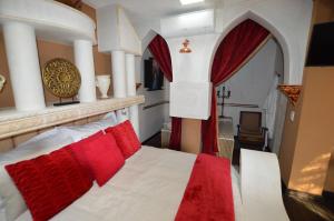 Kiwara Guesthouse في جوهانسبرغ: غرفة نوم بسرير ابيض ومخدات حمراء