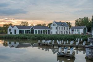 eine Gruppe weißer Gebäude neben einem Wasserkörper in der Unterkunft De Koolputten in Waasmunster