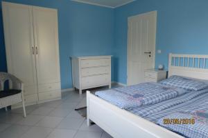 1 dormitorio con cama y pared azul en Landhaus Klein Kubitz WE8864, en Ummanz