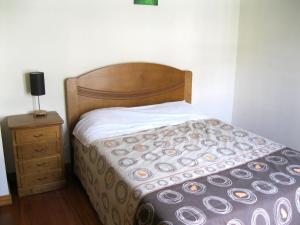 Bett mit einem Kopfteil aus Holz neben einem Nachttisch in der Unterkunft Estacada Apartment in Machico