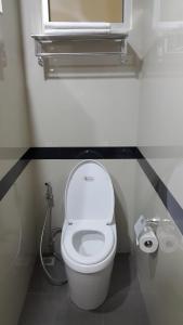 a white toilet in a bathroom with a window at The Supara in Bangkok