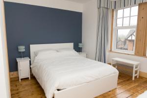 a bedroom with a white bed and a blue wall at The Bay Boutique Bed and Breakfast in Freshwater