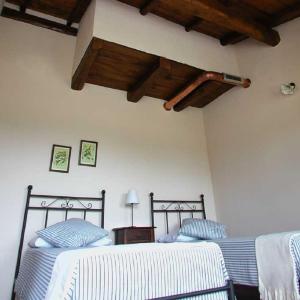 two beds in a bedroom with wooden ceilings at Cascina Formighezzo in Arquata Scrivia