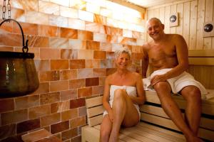 un hombre y una mujer sentados en una sauna en VitalHotel Ascona, en Bad Bevensen
