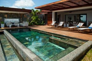 a swimming pool with a patio and a house at Coral Villa in Cap Malheureux