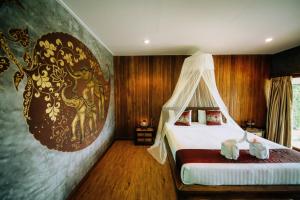 a bedroom with a bed and a painting on the wall at Sawasdee Sukhothai Resort in Sukhothai