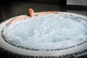 
a woman laying in a pool of water with her head in the water at Hôtel Spa La Cueillette in Meursault
