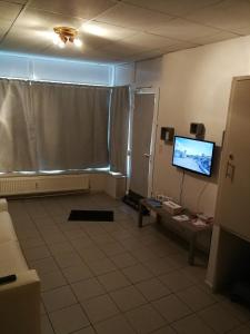 sala de estar con TV y suelo de baldosa. en La clé des vacances en Stavelot