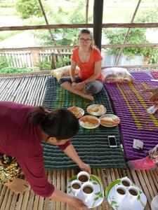 two women sitting on a table with plates of food at Battambang Dream Bungalows in Battambang
