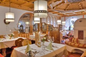 ein Restaurant mit weißen Tischen, Stühlen und Kronleuchtern in der Unterkunft Bergsporthotel Antonie in Gries im Sellrain
