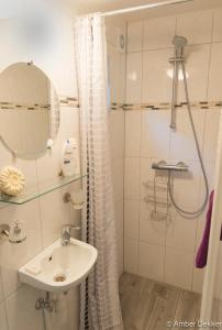 a white bathroom with a sink and a shower at Vrijstaande blokhut in Egmond-Binnen