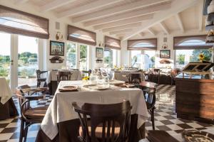 um restaurante com mesas, cadeiras e janelas em Leonardo Trulli Resort em Locorotondo