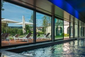 einen Pool mit Stühlen, einem Sonnenschirm und Fenstern in der Unterkunft Château & Spa de la Cueillette in Meursault