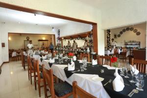 a dining room with long tables and a man in the background at Orient Hotel in Bandarawela