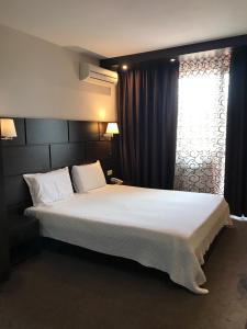 a bedroom with a large bed and a window at Hotel Kardinal in Blagoevgrad