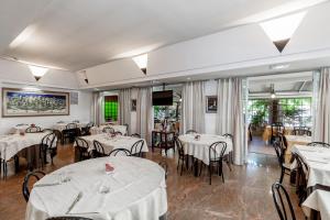Hotel Tevere Perugia في بيروجيا: مطعم به طاولات وكراسي به مفارش بيضاء