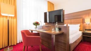 a hotel room with a bed and a desk with a television at Hotel Fürst Bismarck in Hamburg