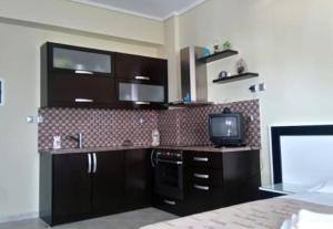 a kitchen with black cabinets and a tv at Villa Xristos Kalogeris in Ksamil +19 photos
