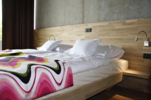 un grande letto bianco con una coperta colorata di Hotel de l'Ecluse Superior a Stadtbredimus