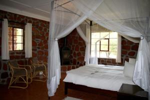 a bedroom with a bed with a canopy and two windows at Waterberg Wilderness - ONE Namibia in Waterberg