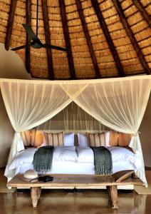 a bed in a room with a roof at Nambiti Plains in Nambiti Game Reserve