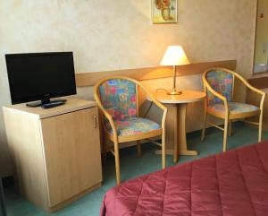 a room with a bed and two chairs and a television at Panorama Hotel Pension Frohnau in Bad Sachsa