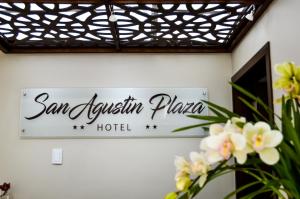 een bord voor het San Ignacio hotel op een muur met bloemen bij Hotel San Agustin Plaza in Latacunga