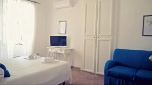 アトラーニにあるVicolo 23 Houseのベッド、青い椅子、テレビが備わる客室です。