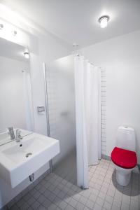 een witte badkamer met een toilet met een rode stoel bij Teaterhotellet in Horsens