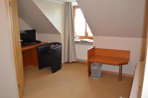 a small room with a desk and a table and a chair at Hotel Daimerwirt in Moosinning