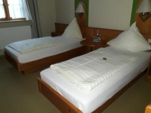 two beds in a hotel room with white sheets at Hotel Daimerwirt in Moosinning