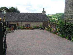 una entrada de ladrillo frente a una casa con flores en The Old Mill and Cottage en Matlock