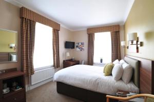 a hotel room with a bed and two windows at The White Lion Hotel in Aldeburgh