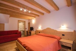 a bedroom with a bed and a red couch at Albergo al Fontanin in Rabbi