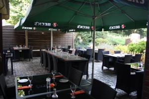 een restaurant met tafels en stoelen en een groene parasol bij Hotel Schwarzer Adler in Moers