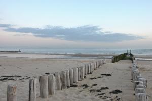 a beach with a wooden fence in the sand at Hotel De Leugenaar in Vlissingen