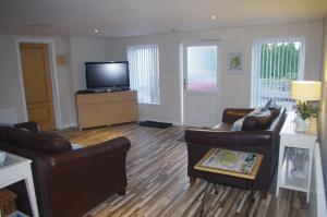 a living room with two couches and a flat screen tv at Gumtree Cottage in Port Askaig