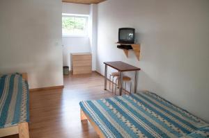 Zimmer mit 2 Betten und einem Tisch mit einem TV in der Unterkunft Dom Wczasowy Dogoda in Zełwągi