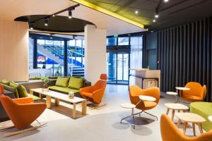 - un hall avec des chaises orange et un canapé vert dans l'établissement Novotel Tours Centre Gare, à Tours