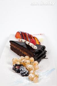 a piece of chocolate cake with fruit on a plate at Hotel Capizzo in Ischia