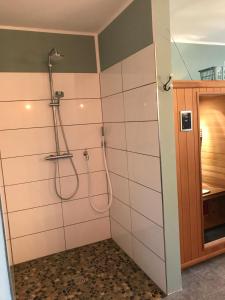 Un baño con ducha con azulejos blancos. en Artgerecht Ferienhäuser, en Bad Berleburg 17 fotos más