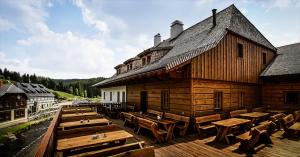 un gran edificio de madera con mesas y sillas de madera en Pivovar Lyer, en Modrava