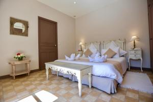 um quarto com uma cama grande com lençóis brancos e almofadas em La Maison de Line em Saint-Rémy-de-Provence