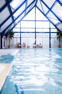 uma grande piscina com tectos azuis e uma grande janela em Ufford Park Resort em Woodbridge