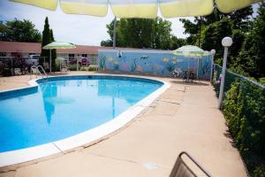 a large swimming pool with a fence and an umbrella at Steelhead Inn in Erie