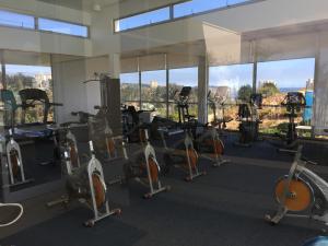 un gimnasio con cintas de correr, elípticas y ventanas en Laguna Bahía Apt. 602, en Algarrobo