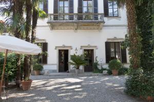 a white house with a balcony and palm trees at Hotel Locanda Dei Mai Intees in Azzate