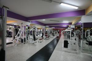 a gym with lots of equipment and purple walls at Hotel all'Antico Pozzo in Barcellona-Pozzo di Gotto
